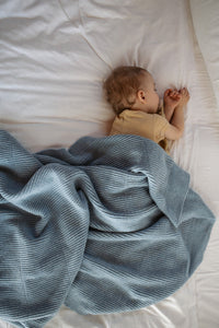 Hvid Gaston Frost Blue — baby onder de blauwe deken op bed